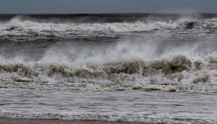 Ondas quebrando na praia com vento terral, criando condições perfeitas para surf. Entendendo Swell, Vento e Marés: Guia Fundamental para Surfistas