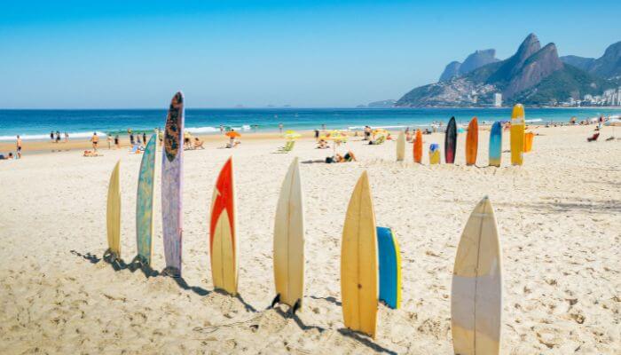 Pranchas de surf de diversos tamanhos enfileiradas na areia, posicionadas verticalmente para ficar em pé. imagem ilustra o artigo 5 Erros Comuns de Principiantes no Surf e Como Evitá-los.