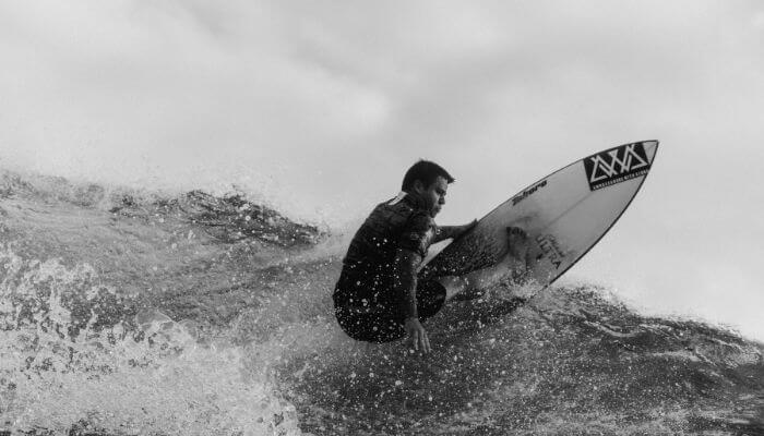 A imagem mostra um surfista em ação, realizando uma batida na onda. Imagem de capa do artigo - História da WSL: Grandes Momentos e Campeões que Moldaram o Surf Profissional